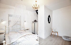 Une chambre à coucher avec un lit, une chaise, une petite table, un miroir et un lustre.