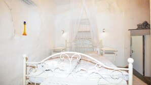 Une chambre à coucher avec un lit en métal blanc, une table de chevet, un lit à baldaquin et une armoire.