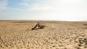 Une plage où est garé, sur le sable, un seul véhicule ancien aux couleurs vives et au style rétro.