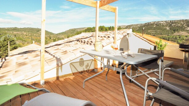 Une terrasse sur le toit, avec une table, des chaises et une vue sur le paysage environnant.