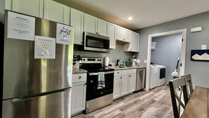 Una cocina moderna con electrodomésticos de acero inoxidable, armarios blancos y piso de madera.