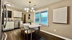 A modern kitchen with white cabinets, stainless steel appliances, and a dining area with a white table and chairs. - 3 BDR Ranch w/ Fenced yard, laundry, garage + more (Liberty Township)