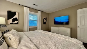 A bedroom with a bed, a television, a dresser, and a window with curtains. - 3 BDR Ranch w/ Fenced yard, laundry, garage + more (Liberty Township)