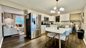 A modern kitchen with a dining area, white cabinetry, stainless steel appliances, and a wooden dining table. - 3 BDR Ranch w/ Fenced yard, laundry, garage + more (Liberty Township)