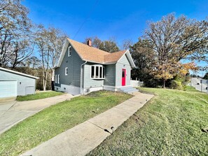 A single-story house with a red door, a front porch, and a small front yard.