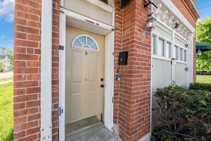 A residential building with a beige front door, a brick exterior, and a garage door. - 101 Crawford Street unit B · Funky Firehouse Renovated into Modern 2 BDR/1 Bath (Middletown)