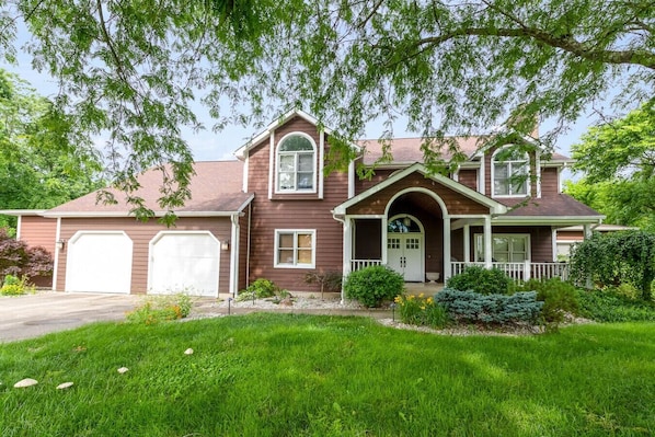 A two-story house with a front porch, a garage, and a well-maintained lawn.