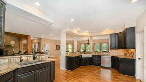 Una cocina amplia con armarios oscuros, encimera de granito y piso de madera.