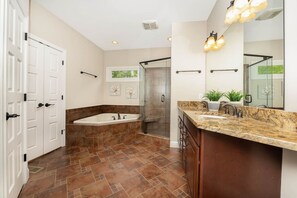 Un bagno con una vasca da bagno ampia, una doccia, un lavabo e uno specchio.
