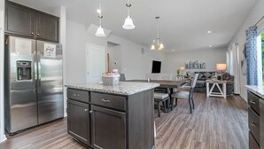 Una cocina moderna con una isla central, electrodomésticos de acero inoxidable e iluminación colgante.