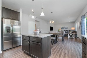 A modern kitchen with a central island, stainless steel appliances, and pendant lighting.