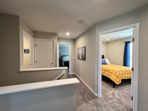 Ein Schlafzimmer mit Bett, einer Tür und einem Flur, der in einen anderen Raum führt.