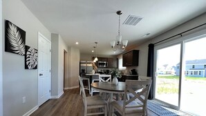 Una cocina moderna con comedor, piso de madera y un amplio ventanal corredizo al exterior.