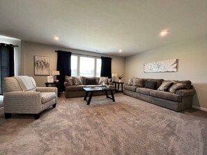 Ein Wohnzimmer mit einem gemusterten Sessel, einer Couch, einem Couchtisch und einem großen abstrakten Gemälde an der Wand.