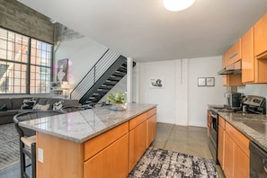 A modern kitchen with granite countertops, wooden cabinets, a built-in oven, and a stainless steel range.