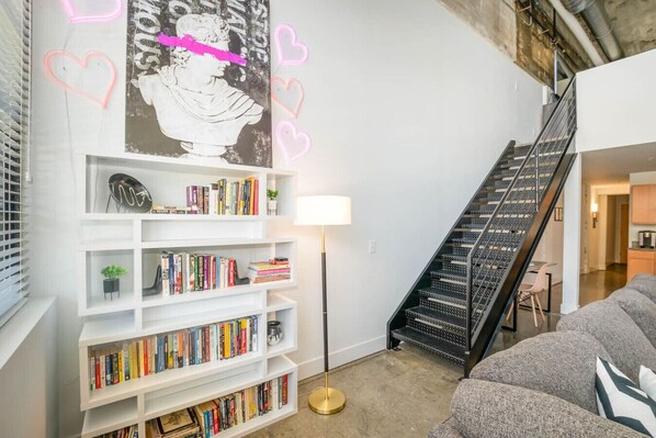 A modern interior with a staircase, bookshelves, and a sofa.
