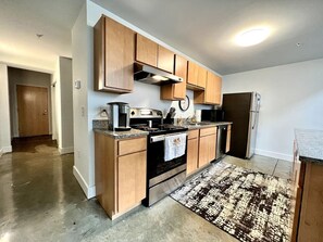 A modern kitchen with wooden cabinets, stainless steel appliances, and a patterned rug.