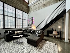 A modern living room with a sectional sofa, a coffee table, and a staircase.