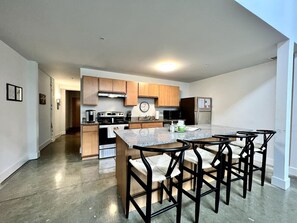 Una cocina moderna con una isla central, taburetes de bar y un comedor.
