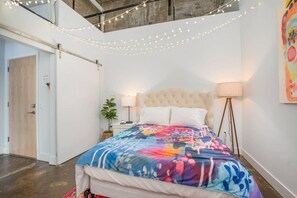 A bedroom with a bed, bedside lamp, and string lights.