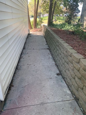 A concrete pathway adjacent to a building with white siding, leading to a stone wall. - 30 Royal #2 · Comfortable Two Bedroom on Royal in Springboro (Springboro)