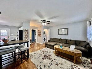 Ein modernes Wohnzimmer mit einer Couch, einem Couchtisch und einem Essbereich mit Stühlen.