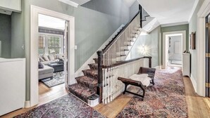 A spacious living area with a staircase, a sofa set, and a patterned rug. - Tower Suite in Historic Mansion B&B, 9 min from Lambeau Field (Green Bay)