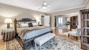 A spacious bedroom with a large bed, a ceiling fan, and a view into the adjacent living area. - Tower Suite in Historic Mansion B&B, 9 min from Lambeau Field (Green Bay)