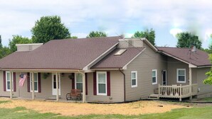A two-story house with a porch, a flag, and a small deck.