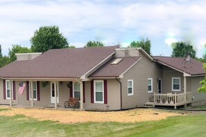 A two-story house with a porch, a flag, and a small deck.