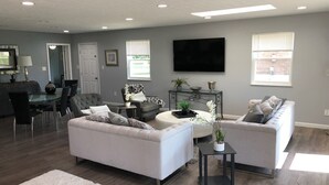 A modern living room with a sofa, armchairs, a coffee table, and a TV.