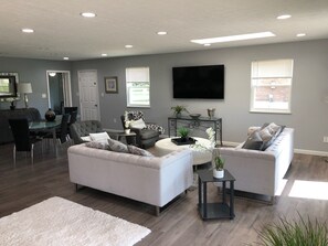 Una sala de estar moderna con un sofá, sillones, una mesa de centro y un televisor.