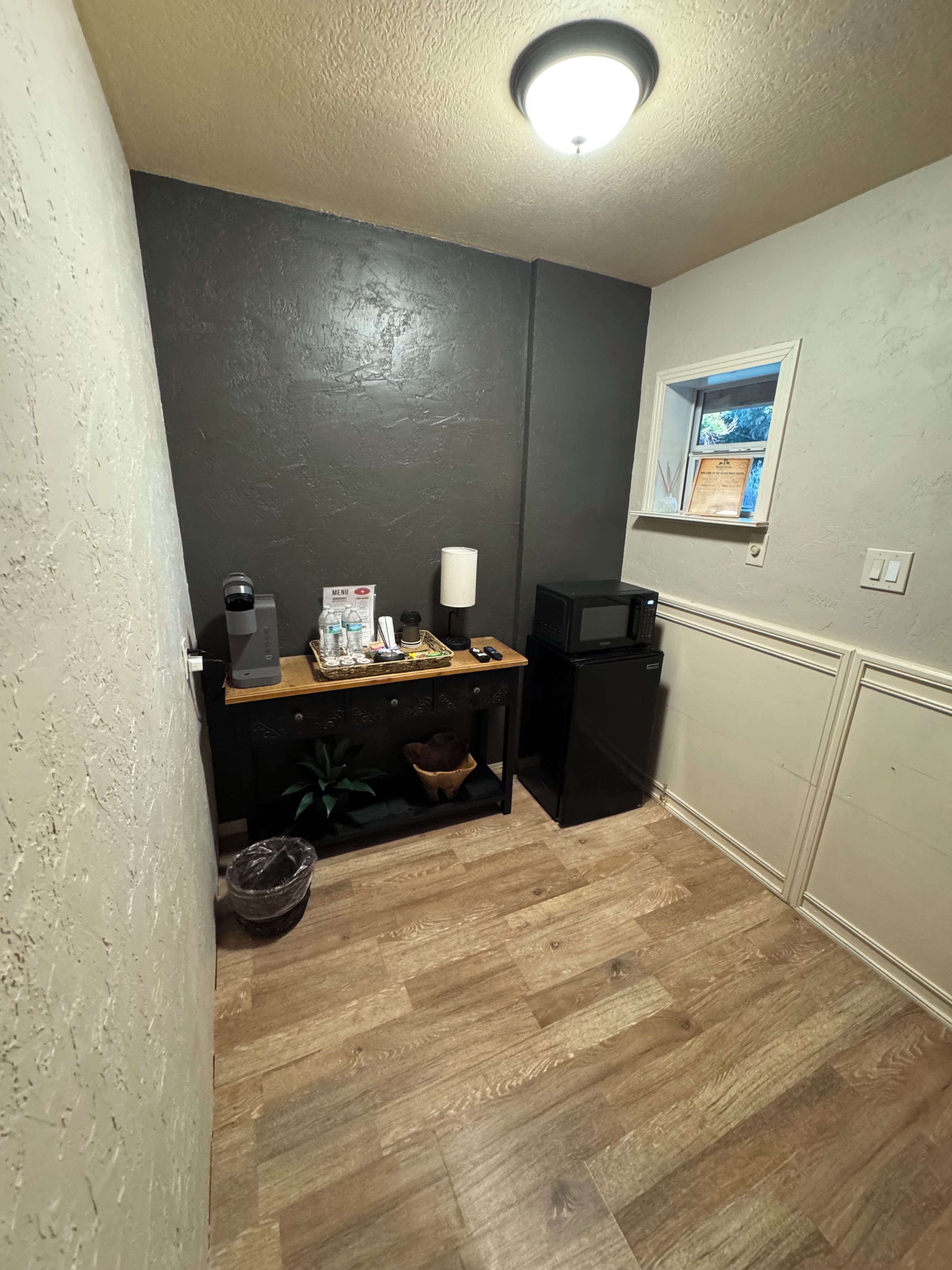 A compact kitchen with a coffee machine, a small refrigerator, and a window with a view.