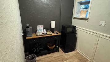 A compact kitchen with a coffee machine, a small refrigerator, and a window with a view.