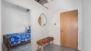 Un dormitorio con cama, una banca, una puerta y un espejo.