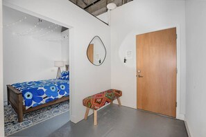 A bedroom with a bed, a bench, a door, and a mirror. - 5103 Peters · New Industrial Loft on Lebanon Bike Trail !! (Maineville)