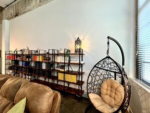 A room with a hanging chair, a bookshelf, and a decorative wall piece.