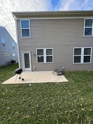 A two-story residential building with a front door, two windows on the ground floor, and a garage door.