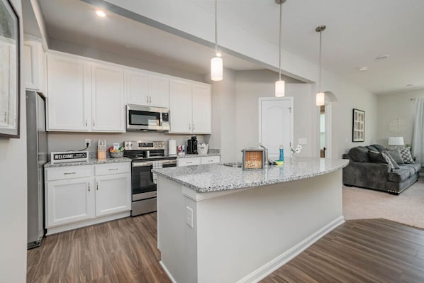 A modern kitchen with white cabinets, stainless steel appliances, and a granite countertop.