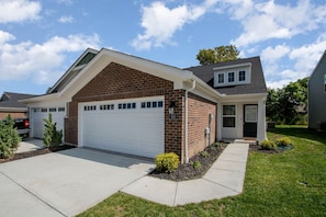 A single-story house with a garage, a brick facade, and a small front yard with landscaping.