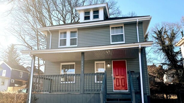 A two-story house with a red door, a covered porch, and a fenced yard. - 3311 Evanston · Large Renovated 4 BDR + Close to DTWN + Laundry (Cincinnati)