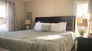 A neatly made bed with a dark headboard, a bedside lamp, and a small plant on a nightstand. - 3311 Evanston · Large Renovated 4 BDR + Close to DTWN + Laundry (Cincinnati)