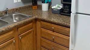 A kitchen with wooden cabinets, a granite countertop, a stainless steel sink, a coffee maker, and a refrigerator. - 5145 Porsche · Newly Remodeled 2 BDRM Ranch- Attached Home (Liberty Township)
