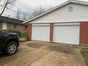 A garage with two white doors, a brick exterior, and a black pickup truck parked in front. - 5145 Porsche · Newly Remodeled 2 BDRM Ranch- Attached Home (Liberty Township)