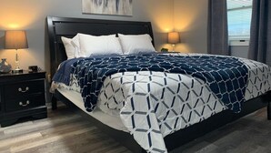 A bedroom with a bed, nightstands, a lamp, a painting, and a window with curtains. - 5145 Porsche · Newly Remodeled 2 BDRM Ranch- Attached Home (Liberty Township)
