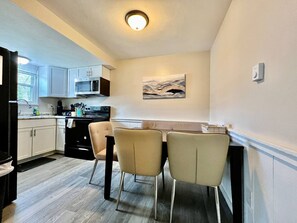 Une cuisine compacte avec un coin repas, comprenant un four à micro-ondes, une cuisinière et des placards.