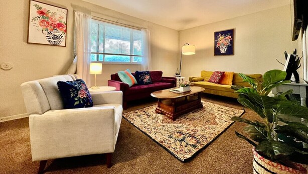 A living room with a sofa, armchair, coffee table, and a potted plant. - Nice Place for the Budget Conscious (Middletown)