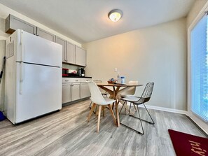 A compact kitchen with a refrigerator, cabinets, and a dining table with chairs. - Nice Place for the Budget Conscious (Middletown)