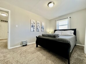 Un dormitorio con cama, ventana con persianas y puerta.