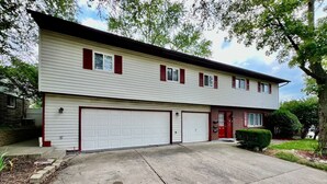 Ein zweigeschossiges Wohnhaus mit Garage, roter Tür und gepflegtem Rasen.